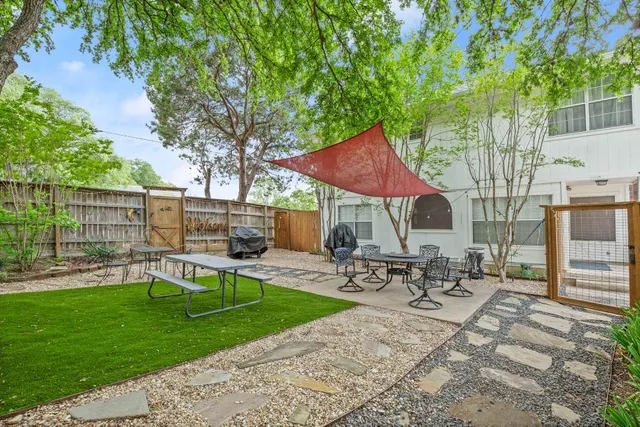 a view of patio with table and chairs under an umbrella with large trees