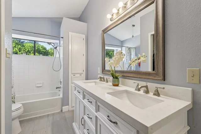 a bathroom with a sink double vanity mirror and a bathtub