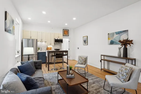 a living room with furniture kitchen view and a window