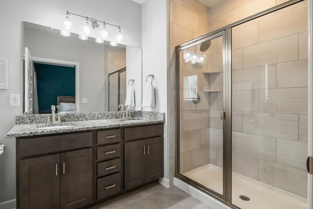 a bathroom with a granite countertop sink a mirror and a shower