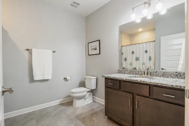 a bathroom with a granite countertop sink a toilet and mirror