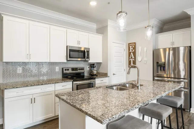 a kitchen with stainless steel appliances granite countertop a sink refrigerator and microwave