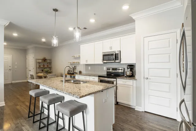 a kitchen with stainless steel appliances granite countertop a stove top oven a refrigerator a sink and a dining table with wooden floor