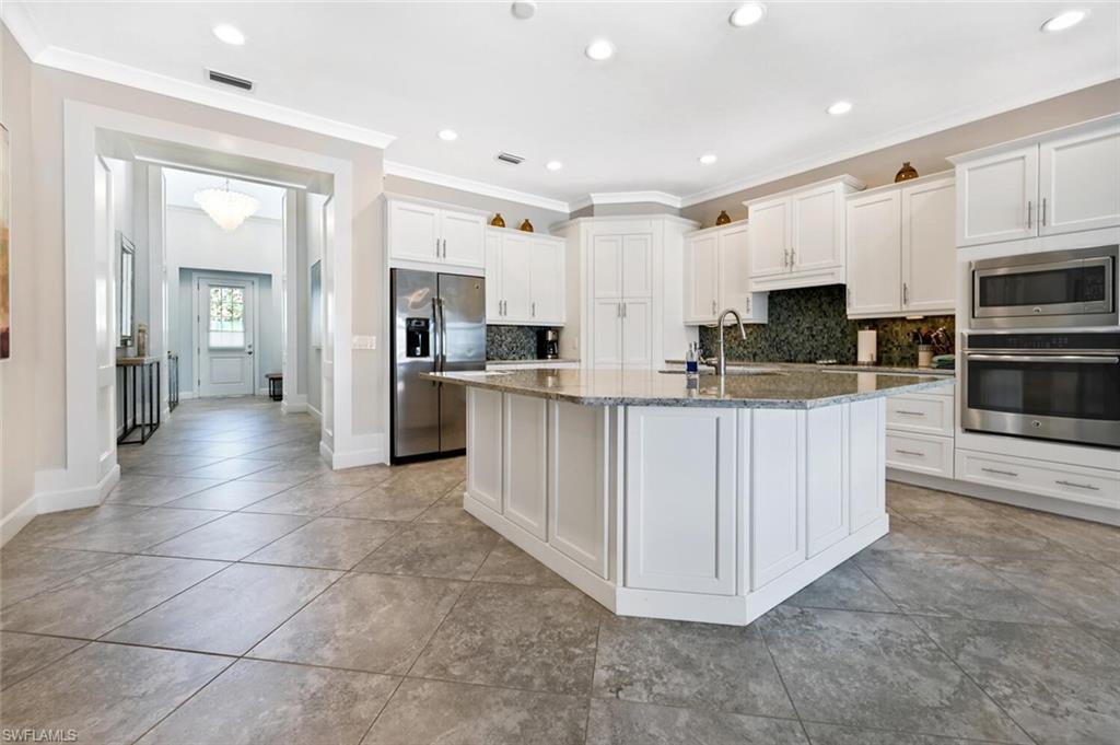 4909 Andros Drive Naples, FL 34113 - Photo 9 of 33 a kitchen with stainless steel appliances a refrigerator sink and cabinets