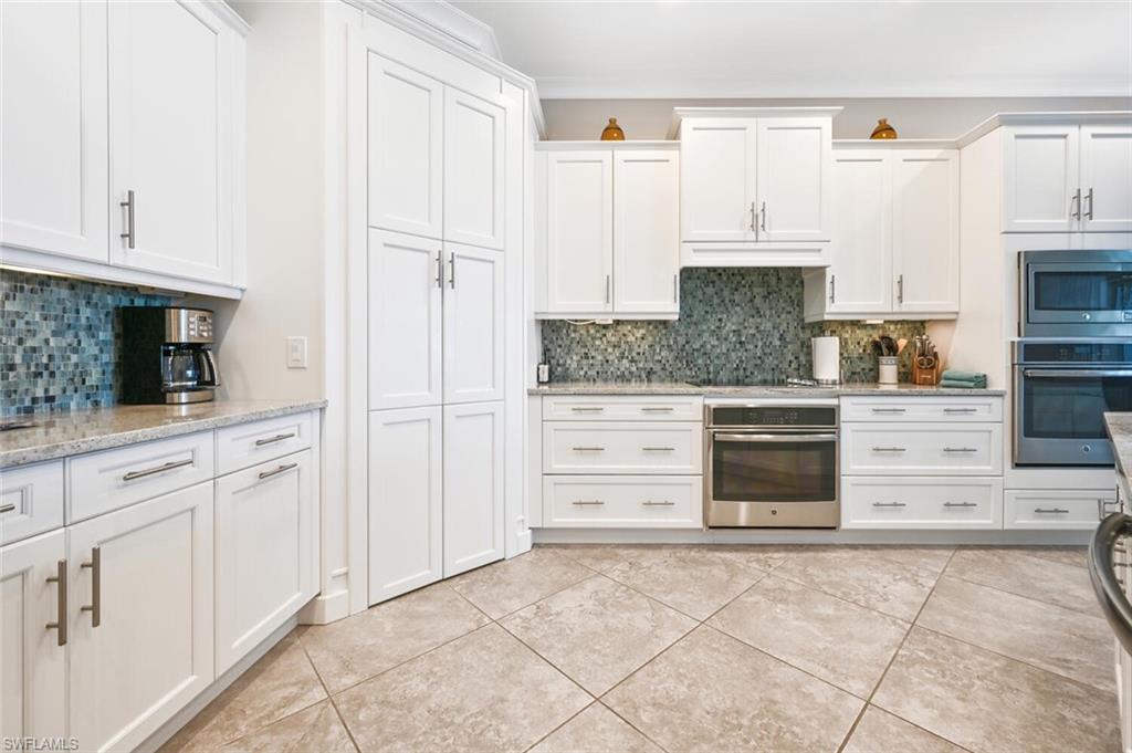 4909 Andros Drive Naples, FL 34113 - Photo 10 of 33 a kitchen with granite countertop a stove top oven and cabinets