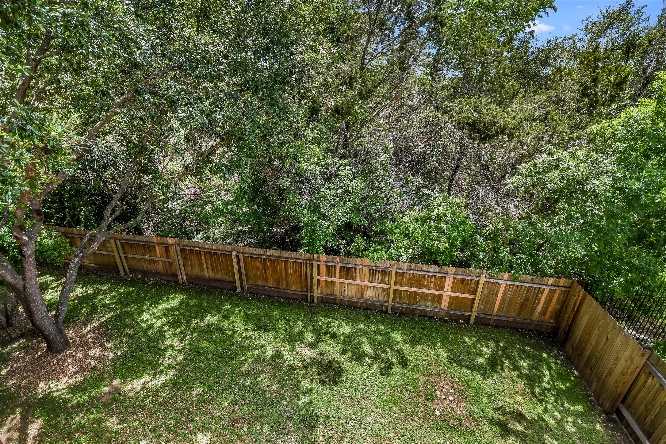 12935 Brigham Drive Austin, TX 78732 - Photo 30 of 35 View of Backyard from Upstairs Deck. Neighboring homes have installed a rod iron fencing to make the greenbelt views even more enjoyable.