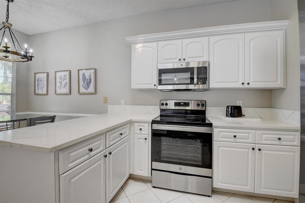 7769 Mansfield Hollow Road Delray Beach, FL 33446 - Photo 13 of 18 a kitchen with white cabinets and stainless steel appliances