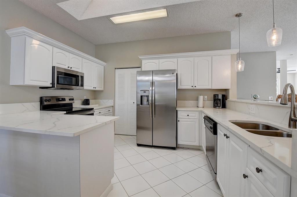 7769 Mansfield Hollow Road Delray Beach, FL 33446 - Photo 14 of 18 a kitchen with a sink a refrigerator and a stove top oven with wooden floor