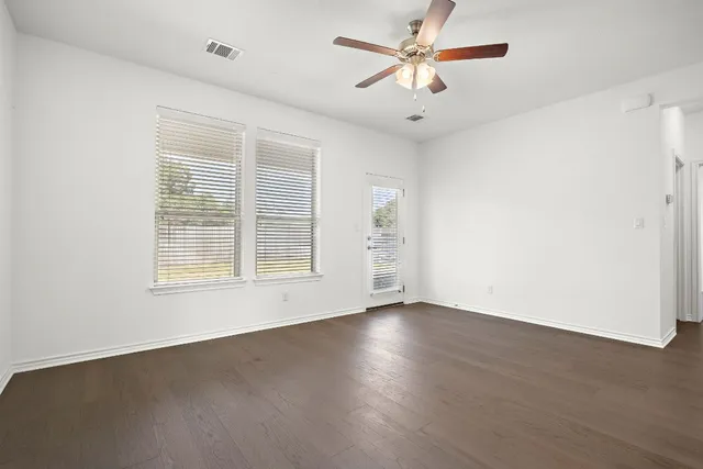 a view of an empty room with a window and a ceiling fan