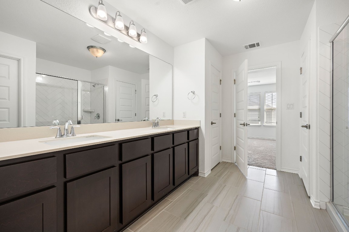 1817 Turtle Bay Loop Leander, TX 78641 - Photo 23 of 38 a spacious bathroom with a double vanity sink a large mirror and a shower