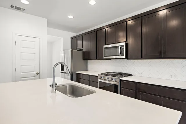 a kitchen with stainless steel appliances wooden cabinets a stove a sink and a refrigerator