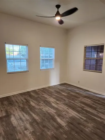 a view of an empty room with a window and wooden floor