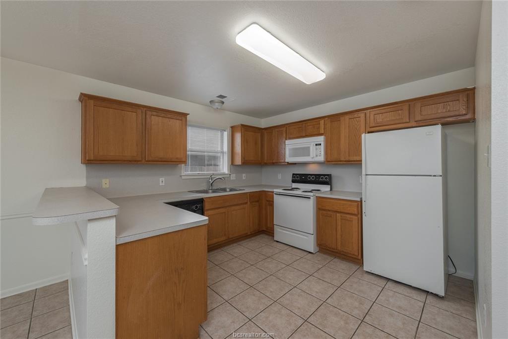 1715 Rock Hollow Loop Bryan, TX 77807 - Photo 4 of 13 a kitchen with a sink a refrigerator and cabinets