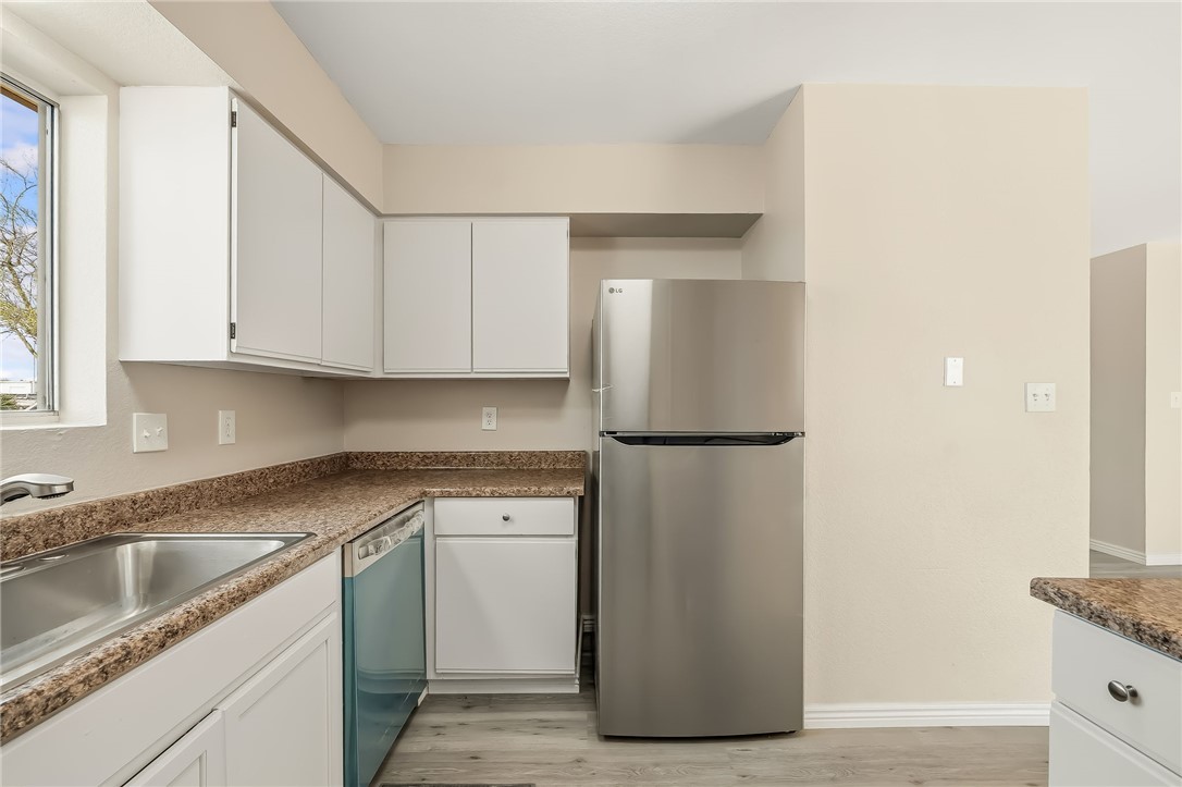 1720 Valencia Road Fort Mohave, AZ 86426 - Photo 12 of 32 Kitchen featuring white cabinetry, wood-finish flooring, a stainless steel refrigerator, a stainless steel sink, and speckled countertops