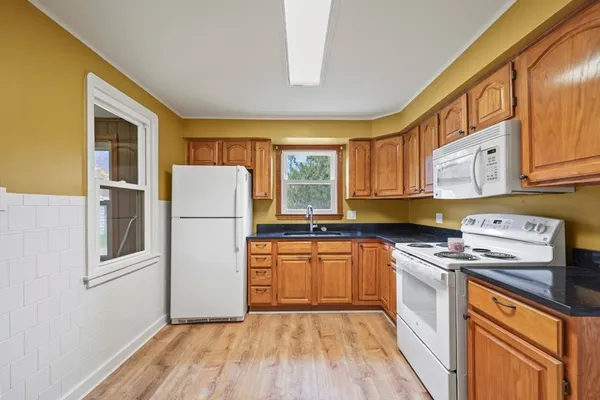 a kitchen with a refrigerator a stove a sink dishwasher and wooden cabinets with wooden floor