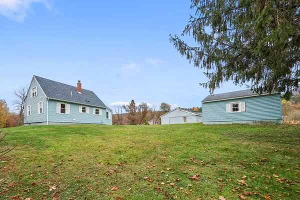 a house that is sitting in the grass with large trees
