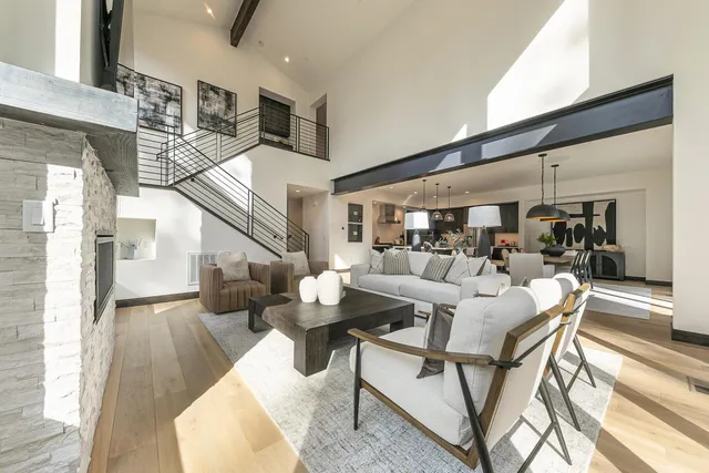 a living room with couches and kitchen view with wooden floor