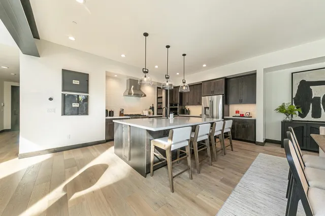 a living room with stainless steel appliances kitchen island granite countertop a table chairs and a stove