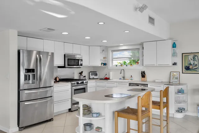 a kitchen with granite countertop a sink stainless steel appliances and white cabinets