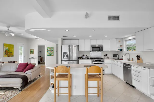 a kitchen with stainless steel appliances granite countertop a stove top oven a sink dishwasher and white cabinets with wooden floor