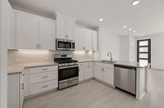 a kitchen with stainless steel appliances granite countertop a refrigerator a sink a stove top oven and a refrigerator