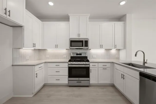 a kitchen with granite countertop white cabinets and stainless steel appliances