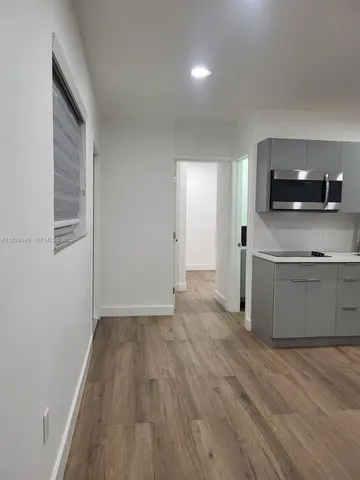 a view of empty room with kitchen and a window