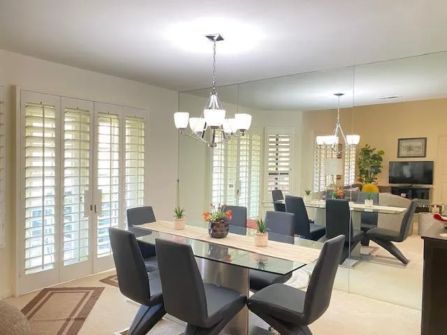 a view of a patio with table and chairs potted plants and floor to ceiling window