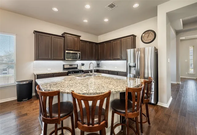 a kitchen with granite countertop a table chairs a sink and a stove