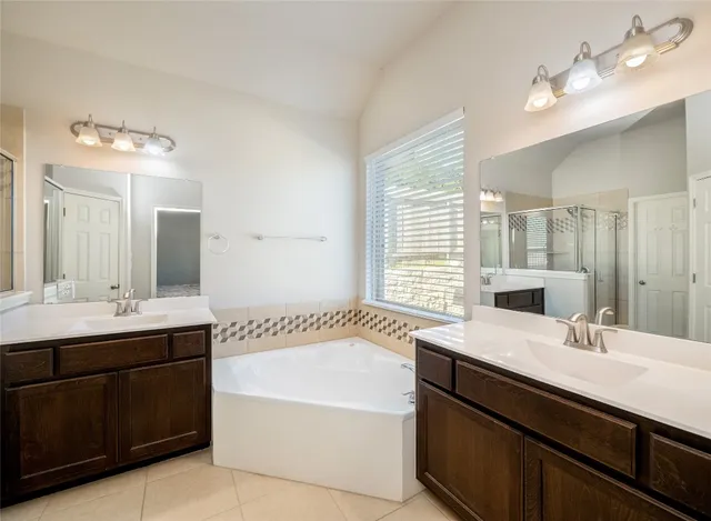 a bathroom with a sink double vanity granite tub and a mirror