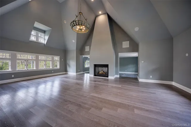 an empty room with wooden floor chandelier and fireplace