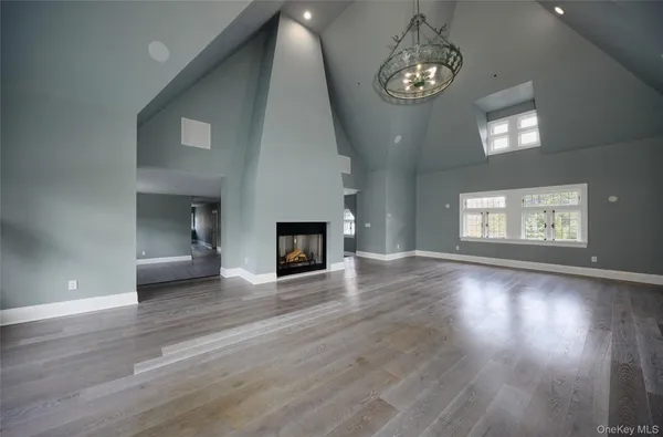 an empty room with wooden floor chandelier and windows