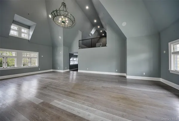 an empty room with wooden floor chandelier and windows