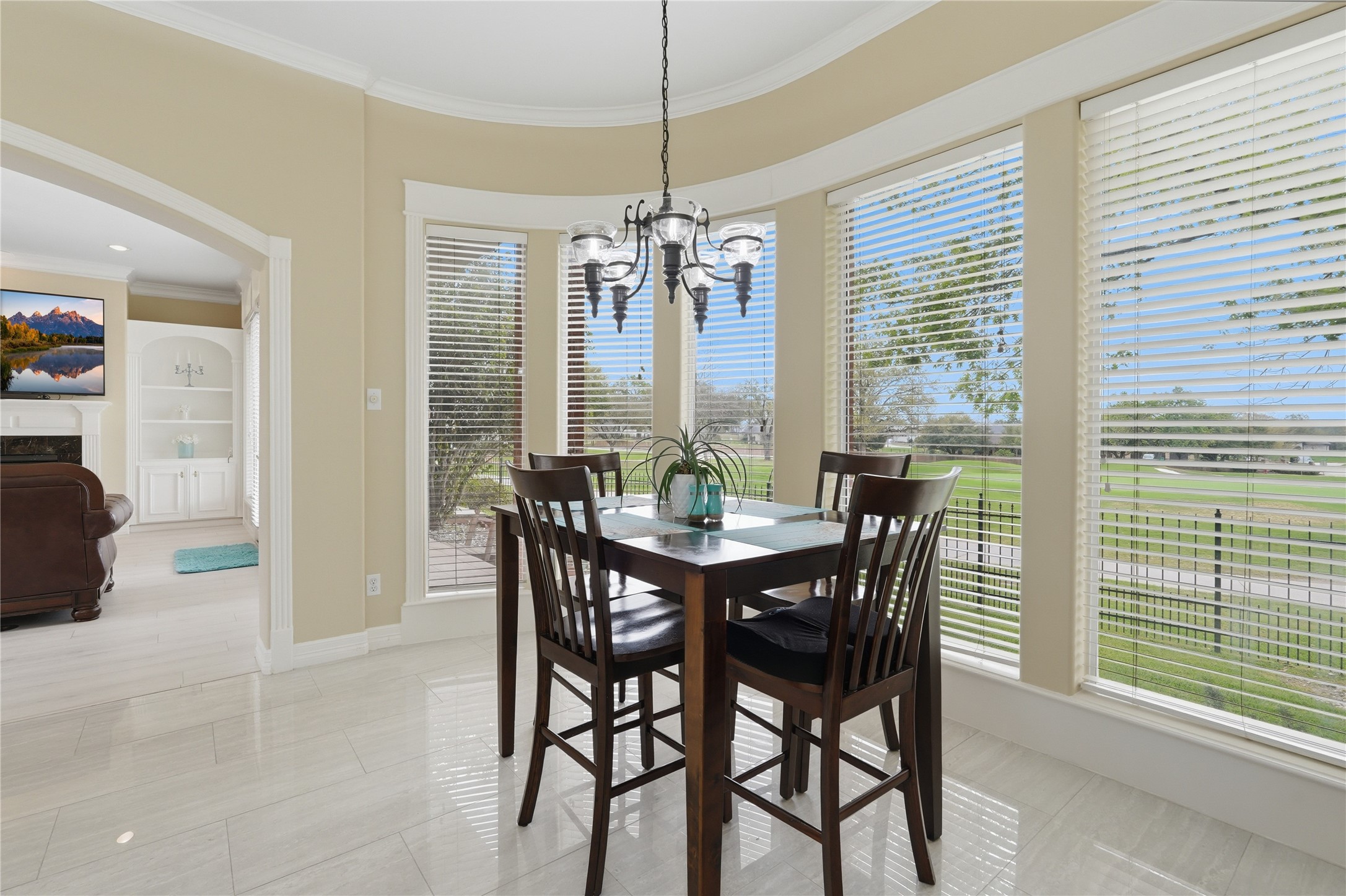 55 Monterrey Road East Montgomery, TX 77356 - Photo 20 of 50 This bright dining area features large windows with a scenic view of lush greenery, a stylish chandelier, and a cozy table setup. The adjacent living space is visible through an arched doorway, enhancing the open layout.