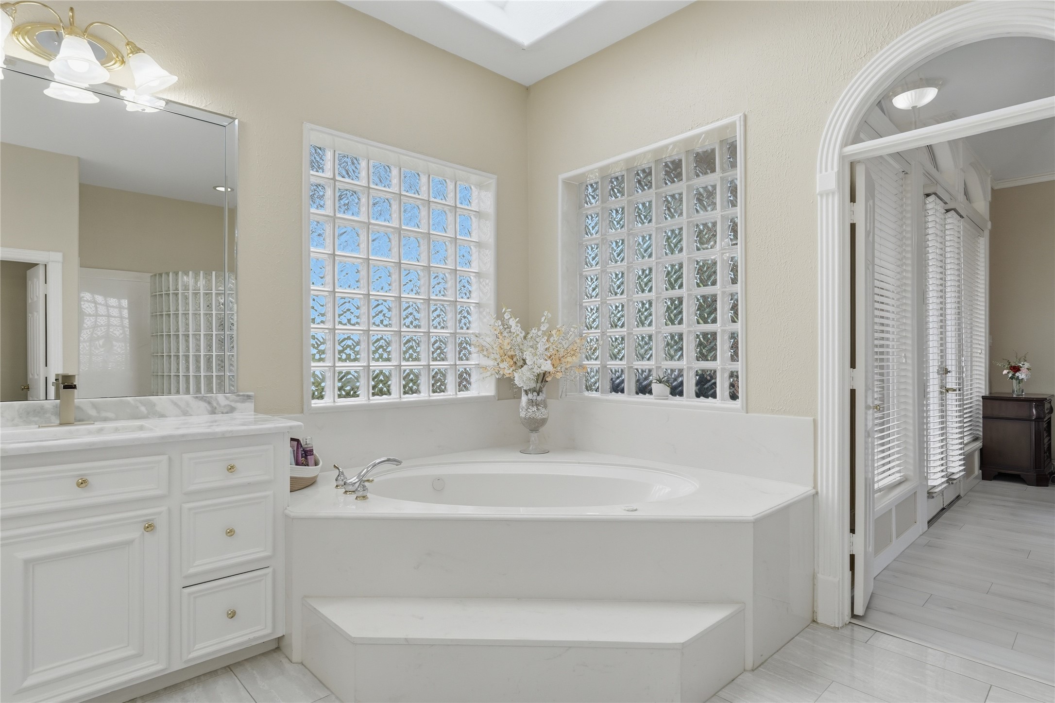 55 Monterrey Road East Montgomery, TX 77356 - Photo 26 of 50 This bathroom features a luxurious soaking tub surrounded by elegant glass block windows, a marble countertop, and ample natural light, creating a serene and inviting space.