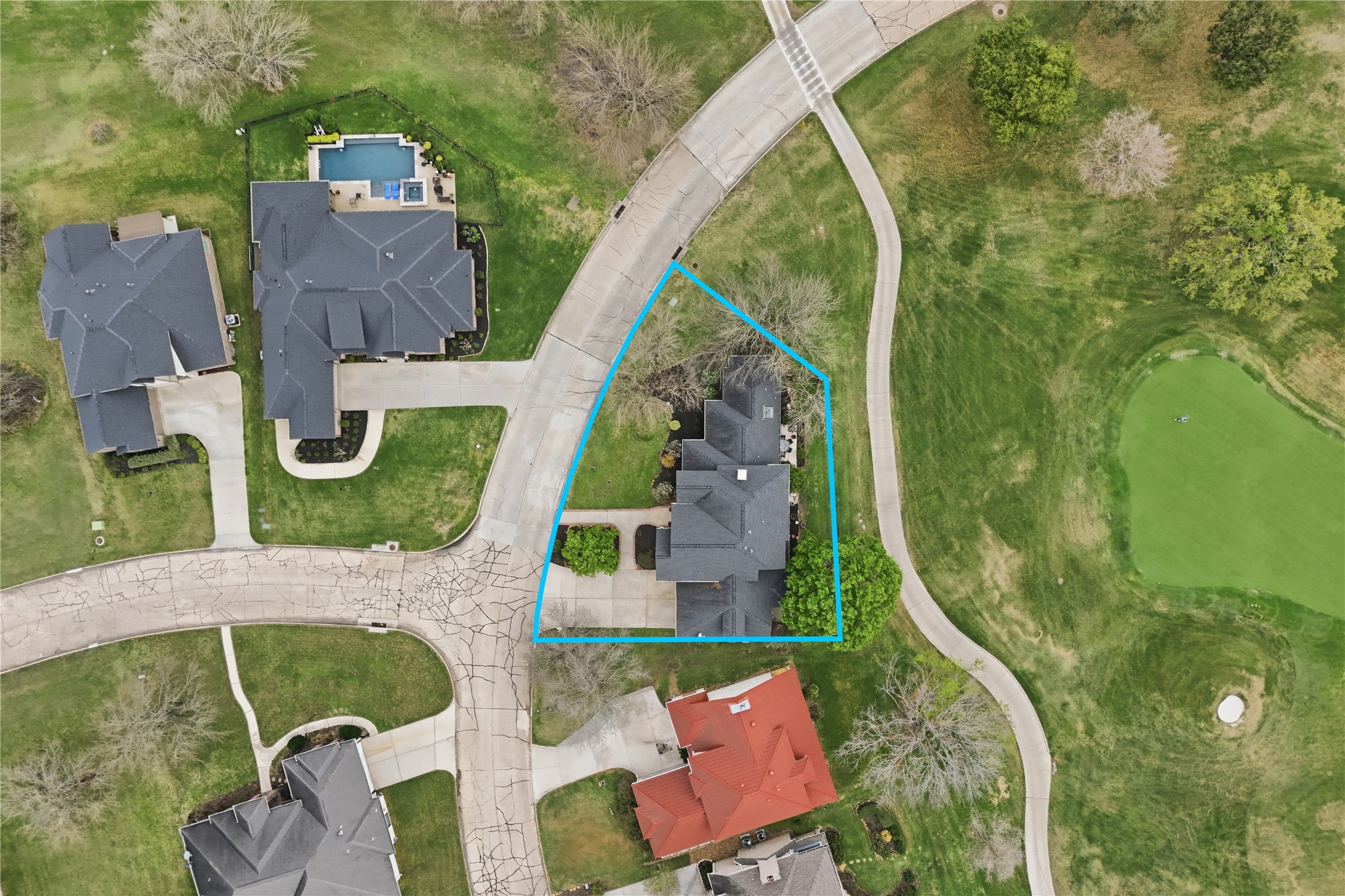 55 Monterrey Road East Montgomery, TX 77356 - Photo 48 of 50 This aerial photo shows a home outlined in blue, situated at a corner lot in a residential neighborhood. The property includes a spacious backyard and is adjacent to a golf course, offering scenic views and easy access for golf enthusiasts. The surrounding area features well-maintained homes, greenery, and a swimming pool nearby.