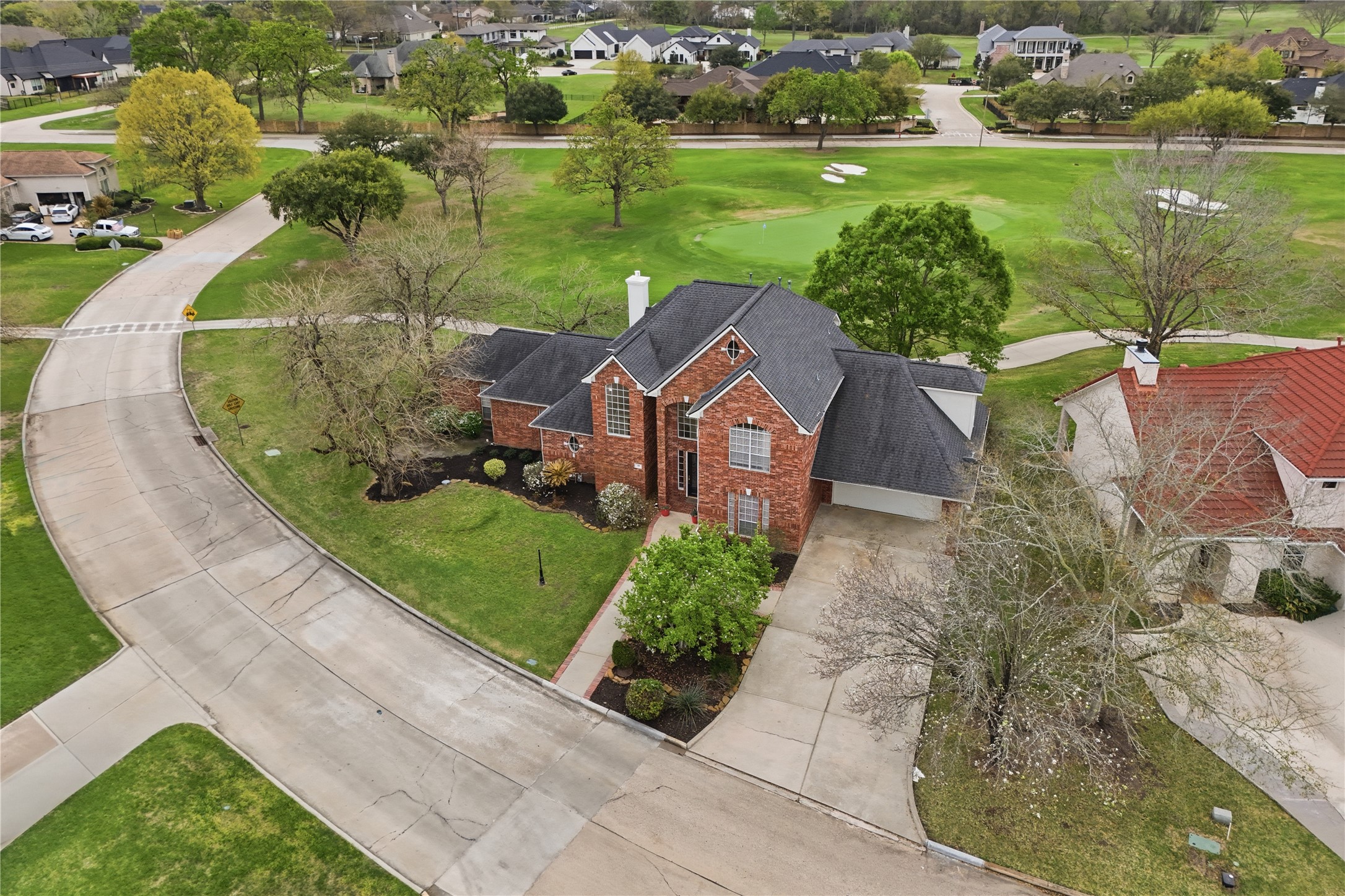 55 Monterrey Road East Montgomery, TX 77356 - Photo 49 of 50 This charming two-story brick home is situated on a corner lot with a spacious driveway. It features a well-manicured lawn and is adjacent to a lush golf course, offering scenic views and a peaceful atmosphere. The surrounding neighborhood is upscale and serene.