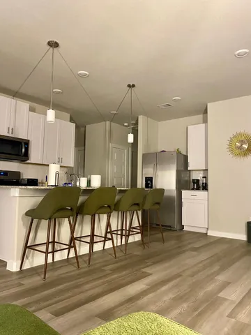 a view of a kitchen with kitchen island a dining table chairs stainless steel appliances and cabinets