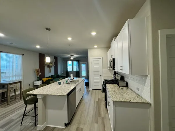 a kitchen with stainless steel appliances kitchen island granite countertop a table chairs and a refrigerator