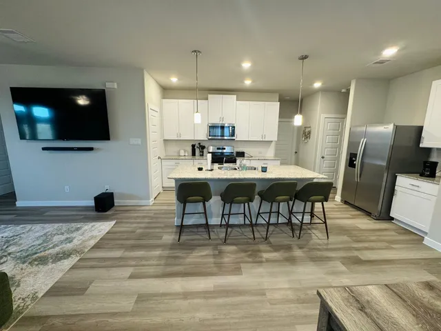 a large kitchen with a counter top space a sink stainless steel appliances and cabinets