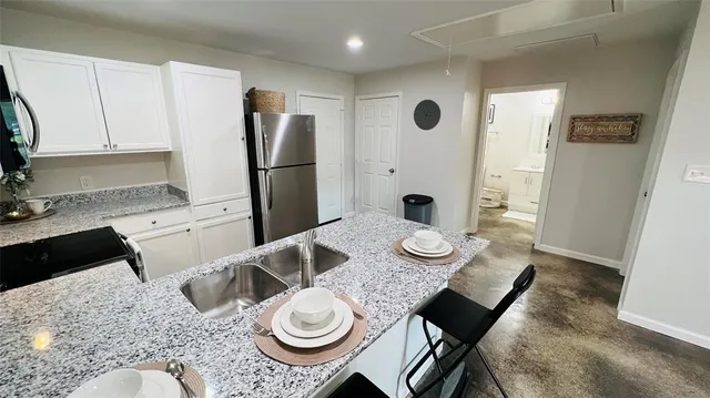a kitchen with sink refrigerator dining table and chairs
