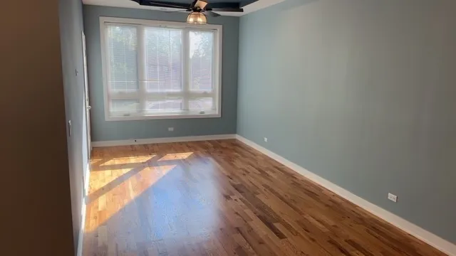 a view of empty room with wooden floor and fan