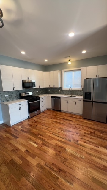 22 North Parkside Avenue, Unit 1 Chicago, IL 60644 - Photo 4 of 13 a large kitchen with stainless steel appliances granite countertop a stove top oven a sink and dishwasher