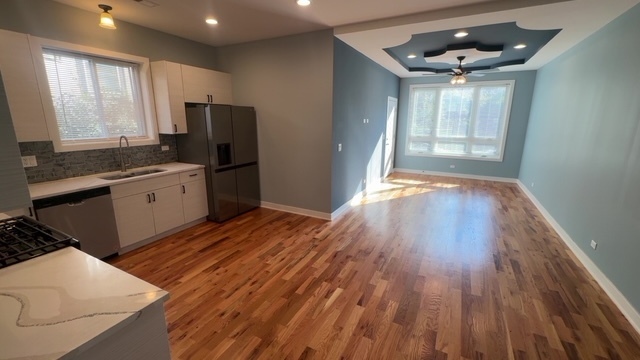 22 North Parkside Avenue, Unit 1 Chicago, IL 60644 - Photo 5 of 13 a kitchen with stainless steel appliances granite countertop a refrigerator a sink dishwasher a stove and white countertops with wooden floor