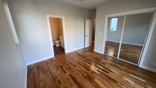 22 North Parkside Avenue, Unit 1 Chicago, IL 60644 - Photo 10 of 13 a bedroom with a bed and wooden floor