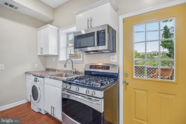 a kitchen with stainless steel appliances white cabinets and a stove top oven