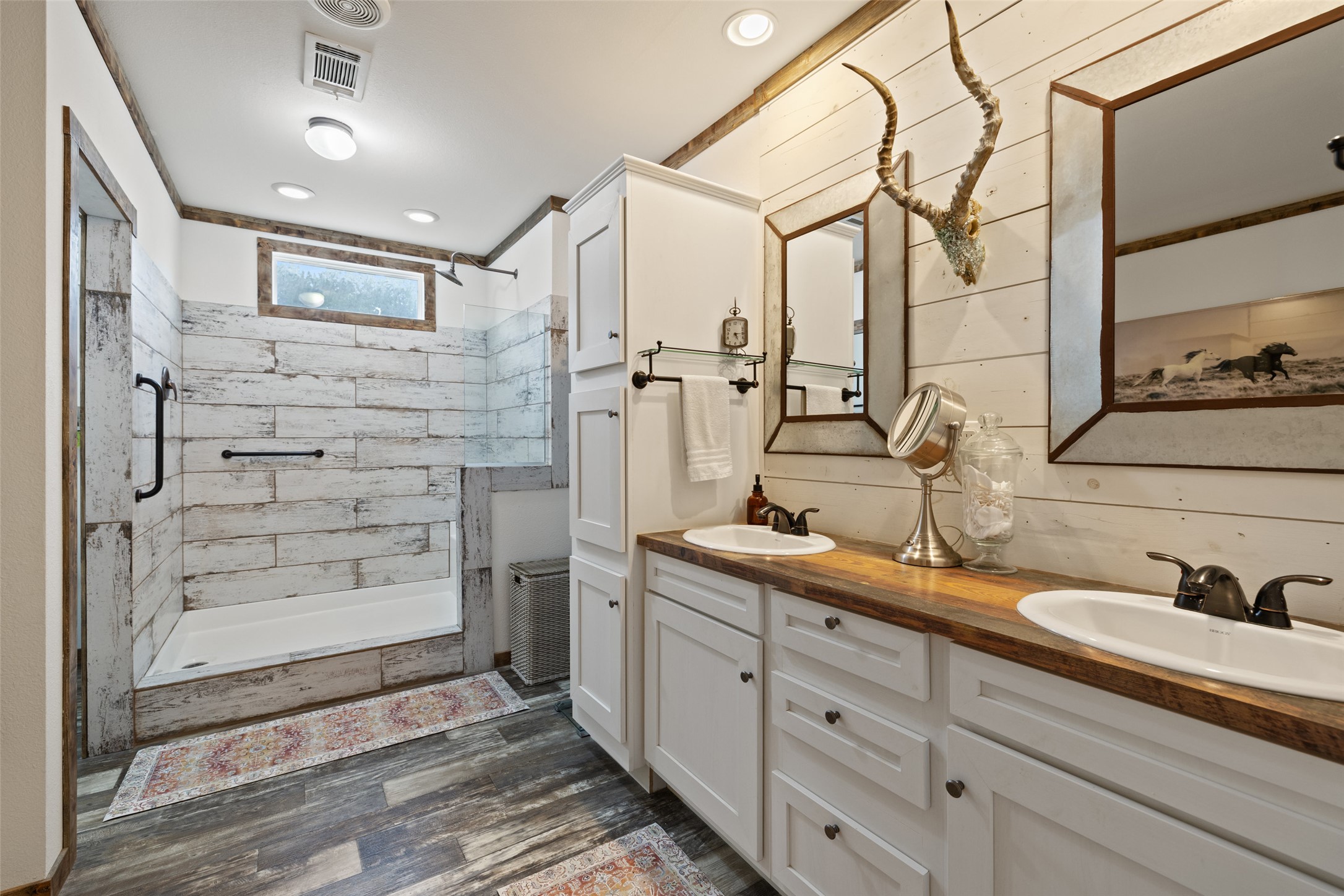 830 Ulrich Road Johnson City, TX 78636 - Photo 24 of 40 A rustic-inspired bathroom with shiplap walls, a dual vanity, and a spacious walk-in shower.