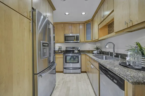 a kitchen with granite countertop a refrigerator stove and sink