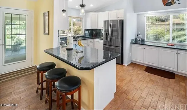 a kitchen with stainless steel appliances granite countertop a stove a refrigerator a sink a dining table and chairs