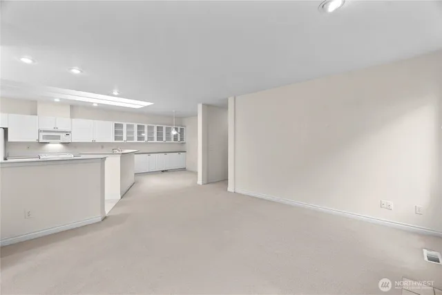 a view of kitchen with refrigerator and white cabinets